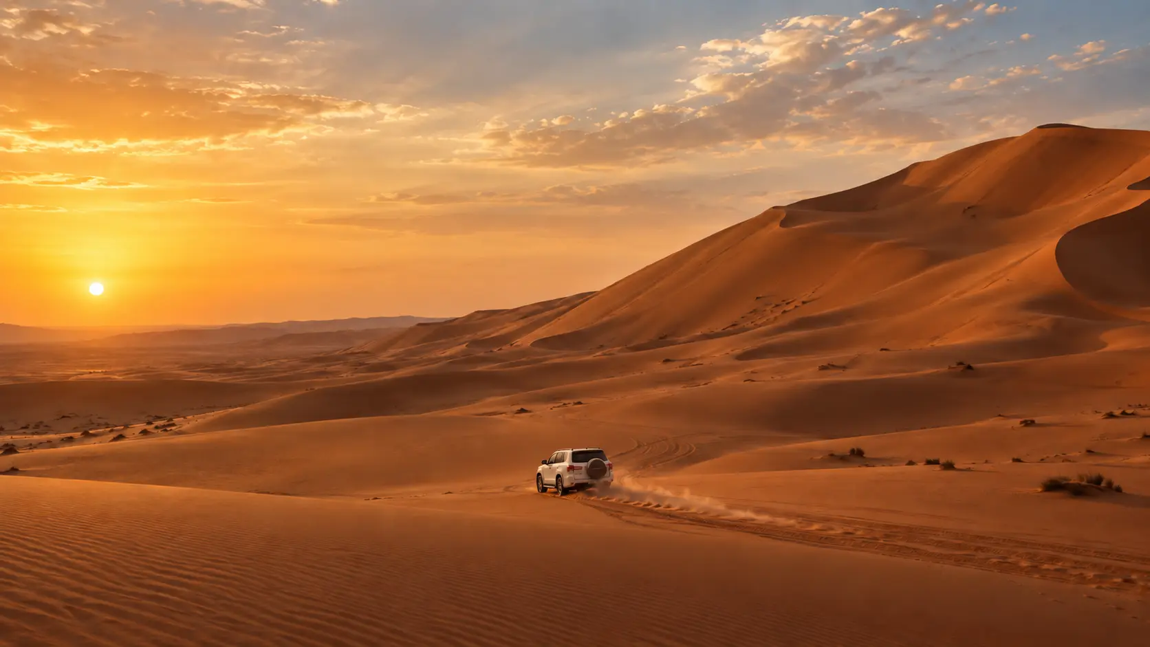 White four-wheel drive crossing the golden dunes of Wahiba Sands at sunset